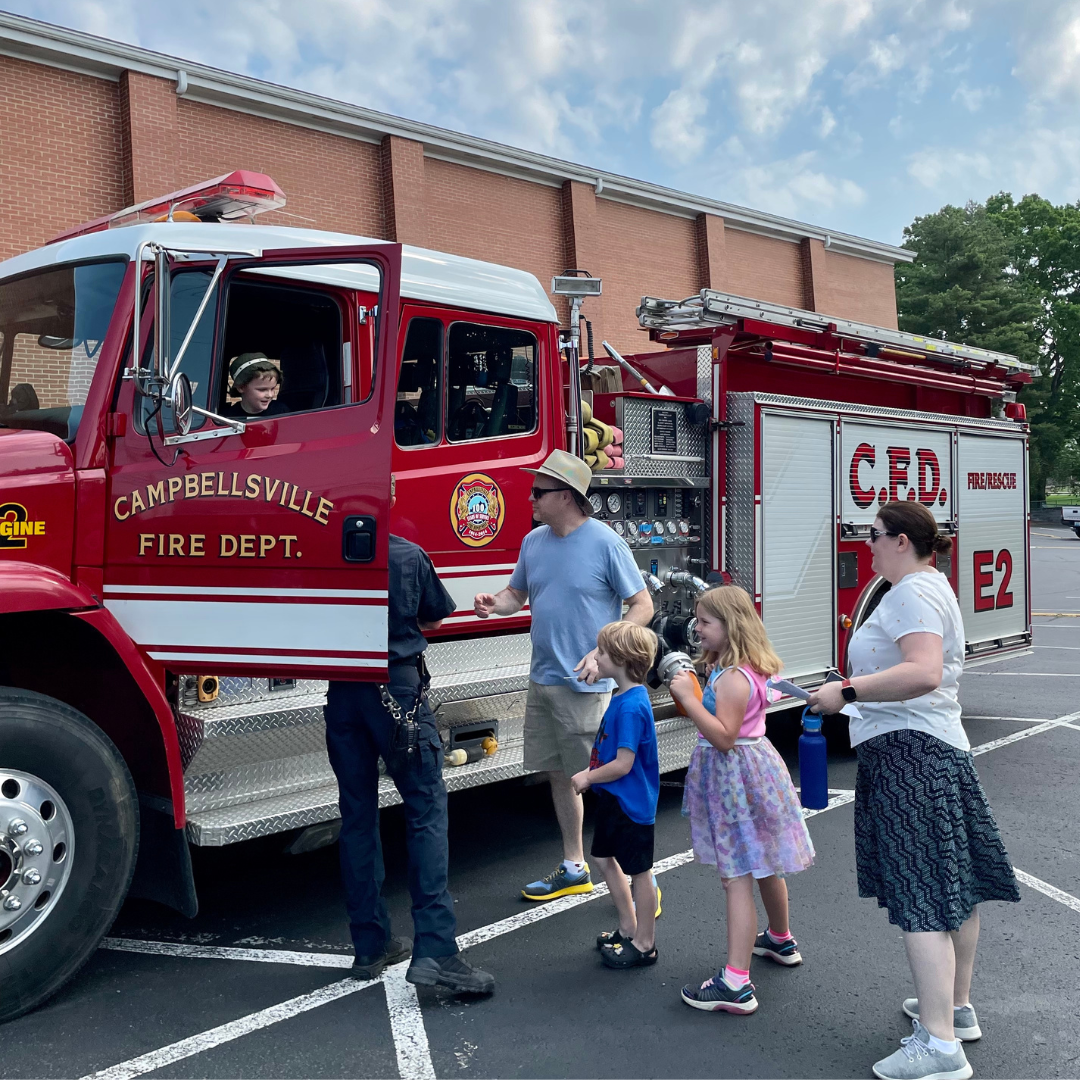 kids and parents sitting in a Fire truck and standing outside