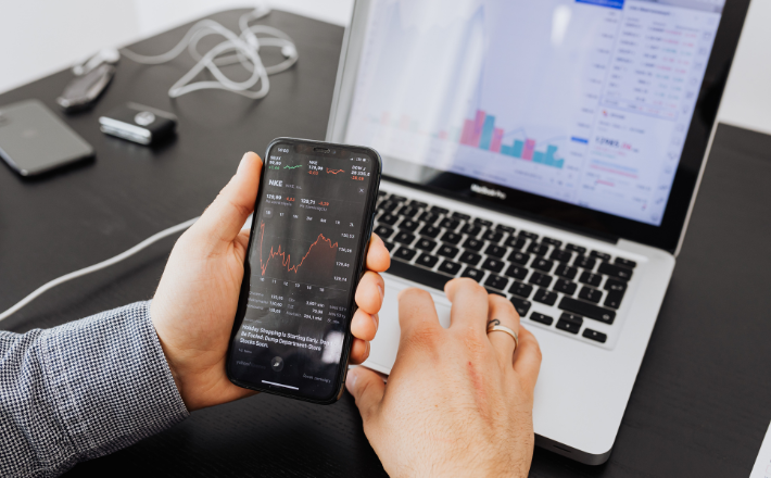 person comparing stocks on their phone to their laptop